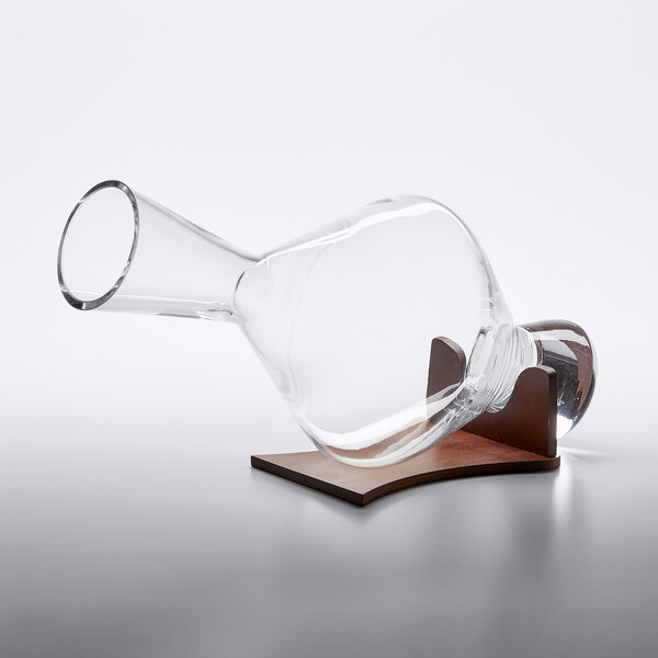 A Stolzle glass decanter on a wooden stand.