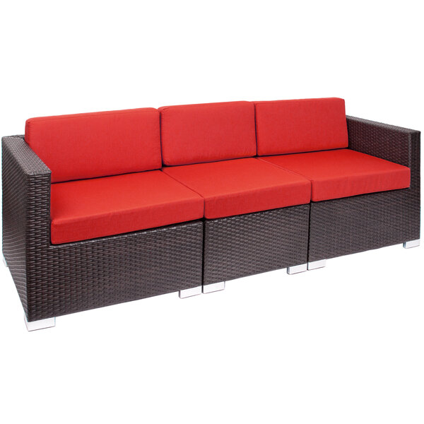 A red cushion on a black wicker outdoor sofa.