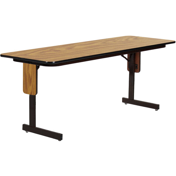A Correll rectangular seminar table with a medium oak top and black panel legs.