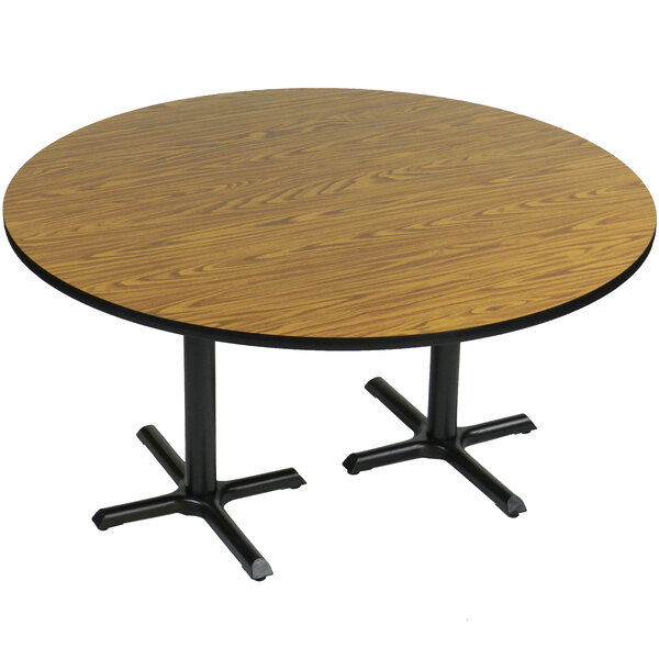 A Correll round table with medium oak finish and two black metal cross bases.