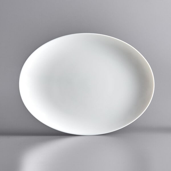 An Arcoroc white oval glass plate on a gray surface.