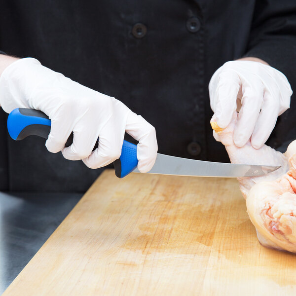 A person wearing white gloves using a Mercer Millennia Colors boning knife with a blue handle to cut chicken.
