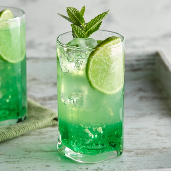 A glass of green liquid with lime slices.
