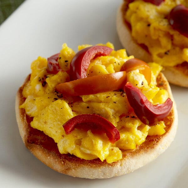 Sliced cherry peppers on two egg muffins on a plate.