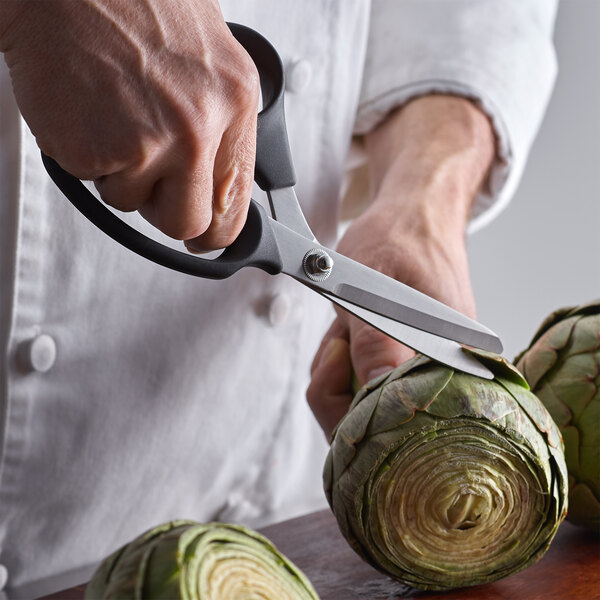 A person using ARY VacMaster black kitchen shears to cut artichokes.