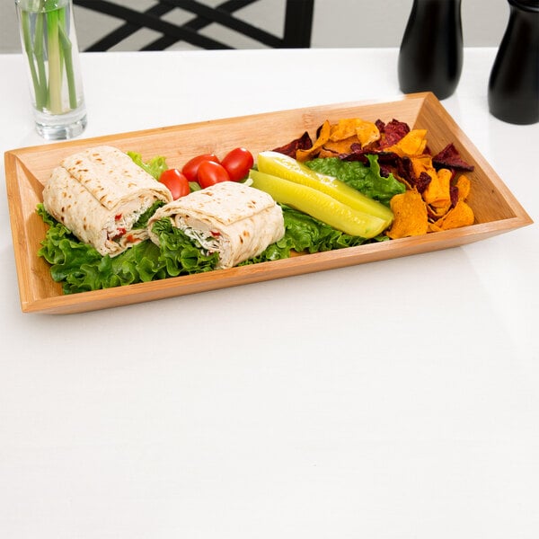 A rectangular bamboo tray with food on a wooden table.