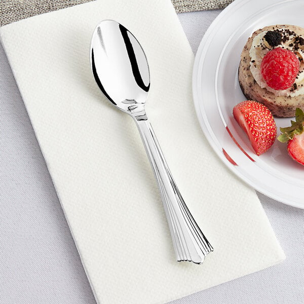 A Visions heavy weight silver plastic spoon on a plate with strawberries.
