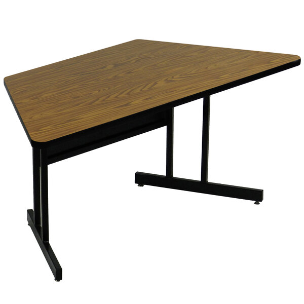 A trapezoid medium oak table with black metal legs.