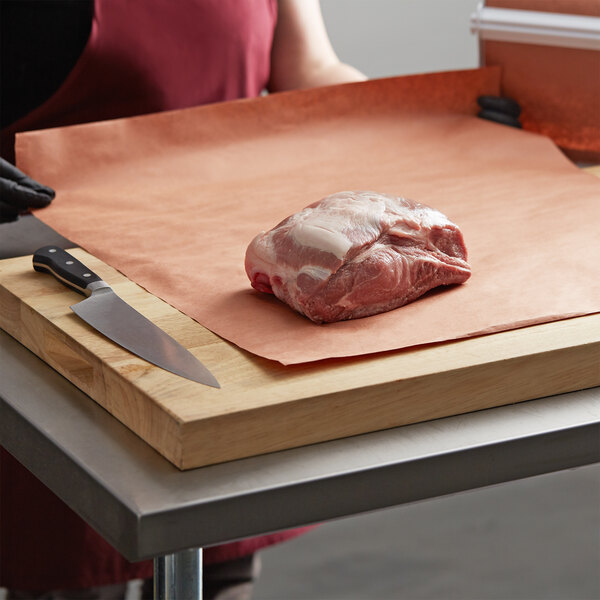 A person cutting a piece of meat on a cutting board.