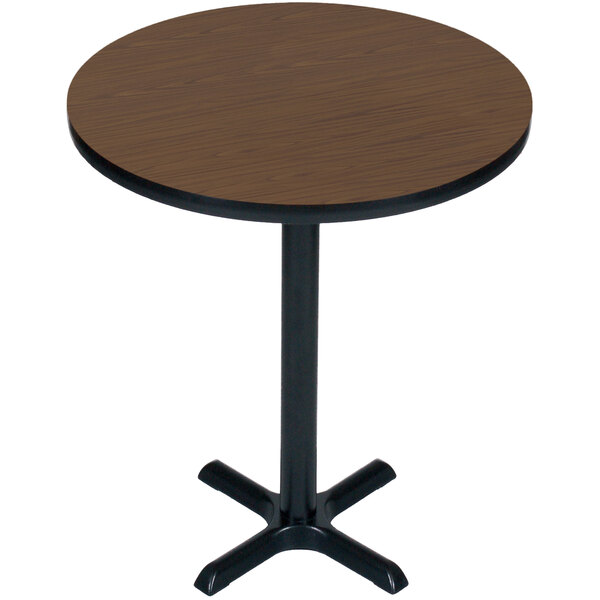 A Correll round walnut bar height table with a black base.