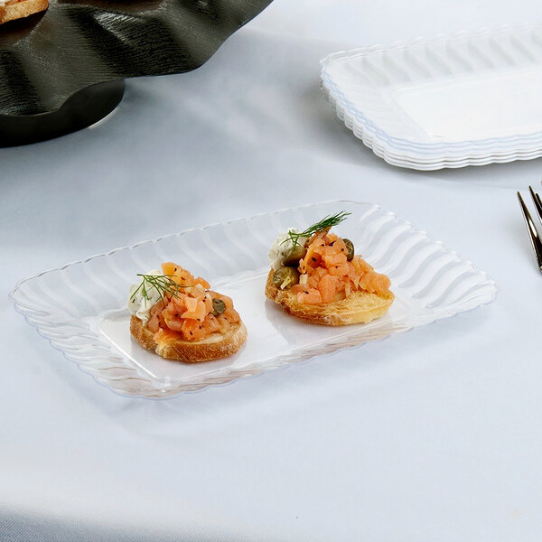 A Fineline Flairware clear plastic snack tray with food on a table.