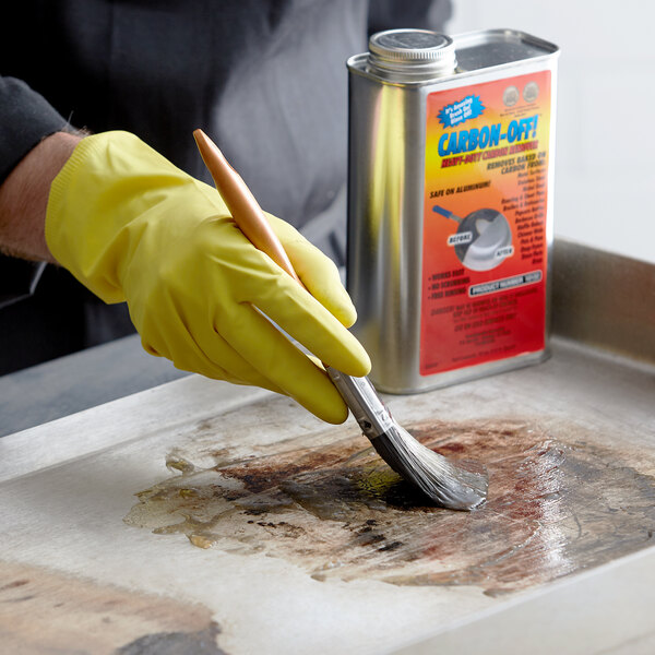 A person in yellow gloves cleaning a tray with a paint brush using Carbon-Off.