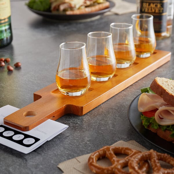 An Acopa flight paddle with whiskey glasses on a table with a flight of whiskey.