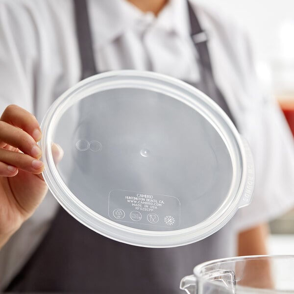 A woman holding a Cambro translucent plastic lid.
