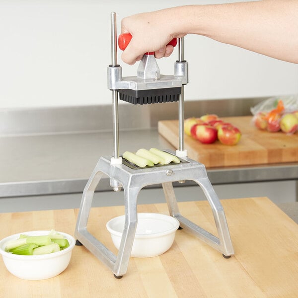 A person using a Vollrath Redco InstaCut 3.5 to dice celery into a white bowl.