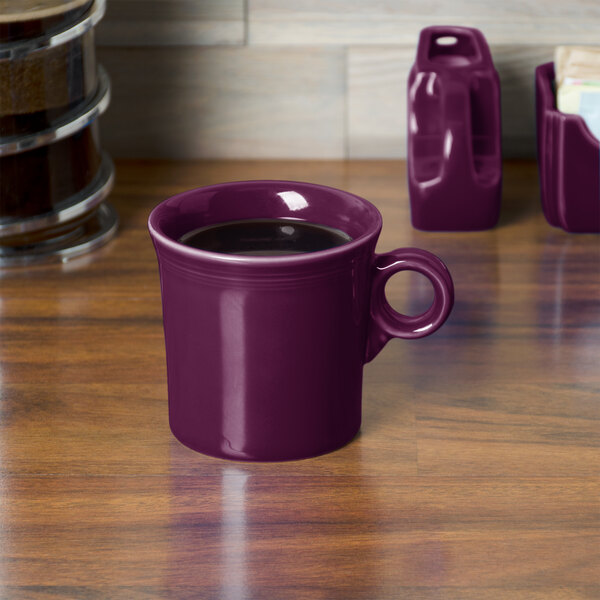 A purple Fiesta china mug on a wooden table.