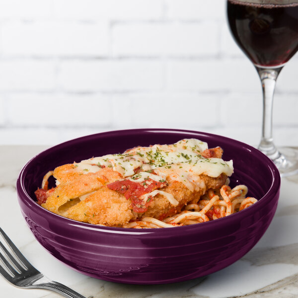 A Mulberry Fiesta china bistro bowl filled with food next to a glass of red wine.