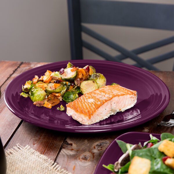 A close up of a Fiesta® Mulberry round chop plate with a piece of salmon and brussels sprouts on it.