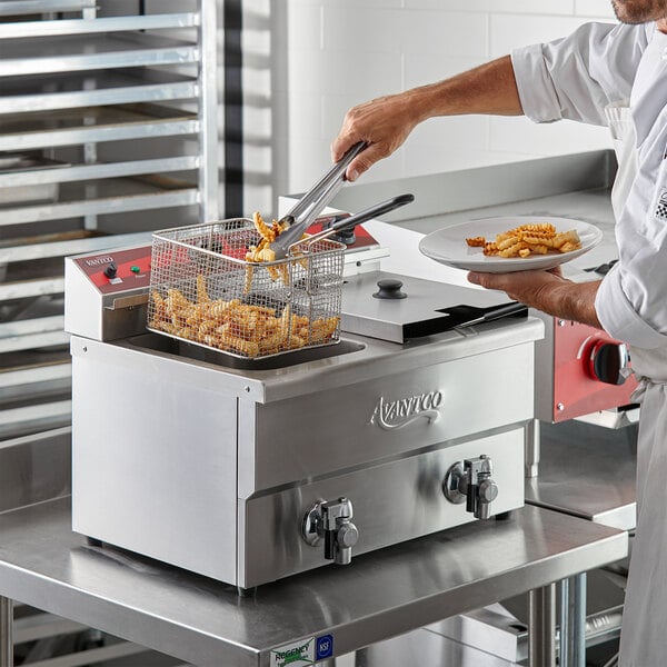A chef using an Avantco electric countertop fryer to cook French fries.