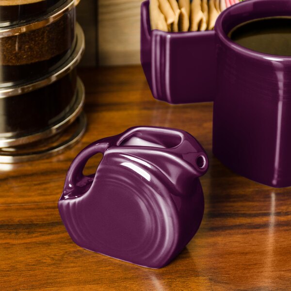 A purple Fiesta mini disc creamer pitcher on a wood surface.