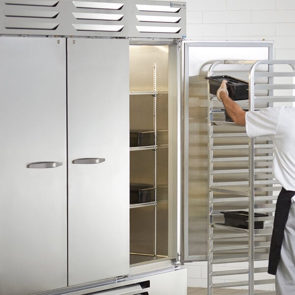 A man in a white shirt opening a Beverage-Air reach-in freezer with solid doors.