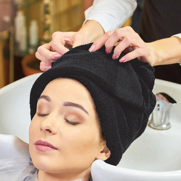 A woman with a black towel on her head getting her hair washed.