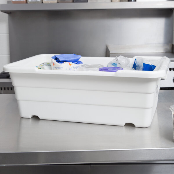 A Winholt white plastic lug on a counter with plastic containers inside.