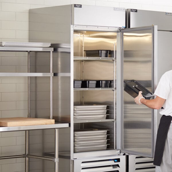 A man in a white shirt using a Beverage-Air Horizon Series reach-in freezer with a black rectangular object.