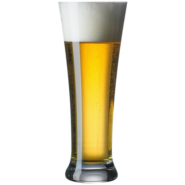 A close-up of a Arcoroc Martigues Pilsner Glass full of beer with foam.