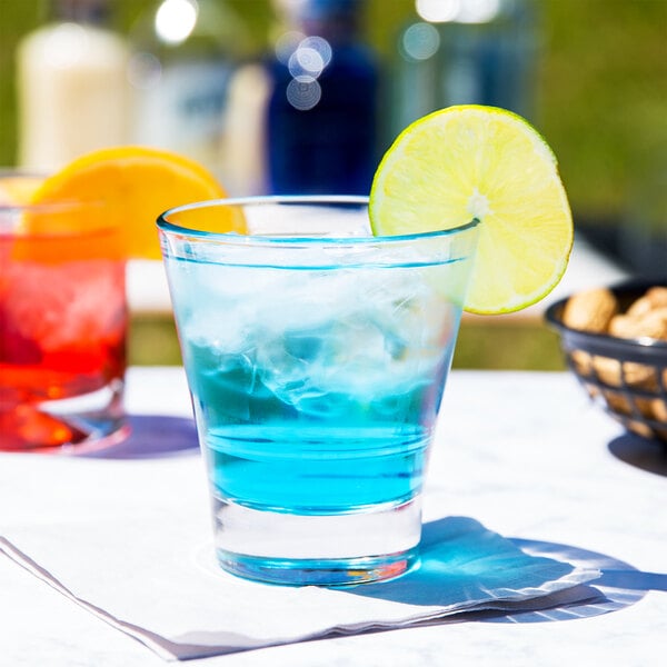 A Libbey stackable rocks glass with blue liquid, ice, and a lime wedge.