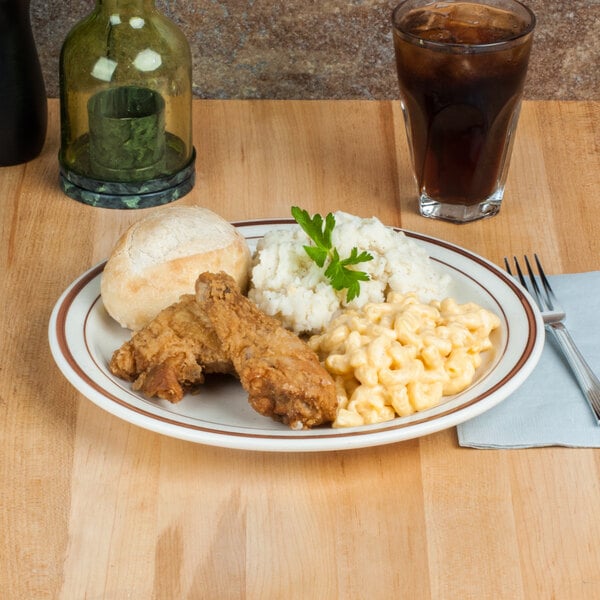 A Libbey narrow rim stoneware plate with fried chicken, mashed potatoes, and macaroni on a table.