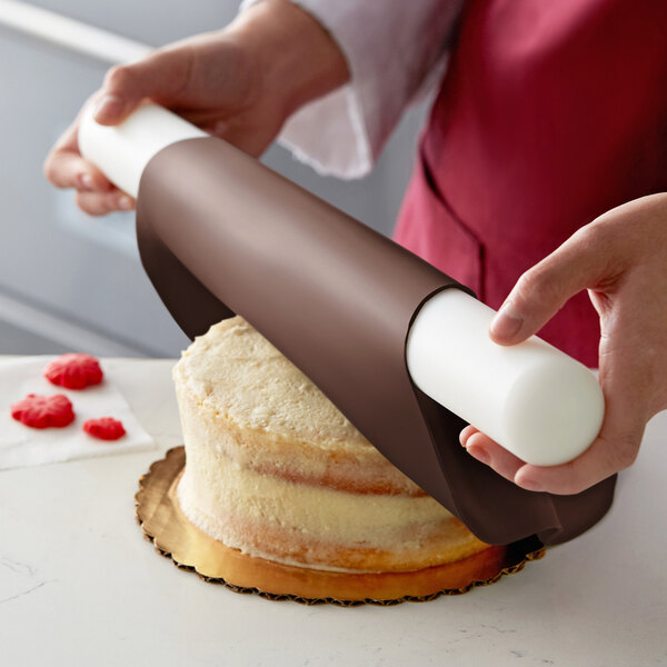 A person using Satin Ice ChocoPan to cover a cake with a pastry cutter.