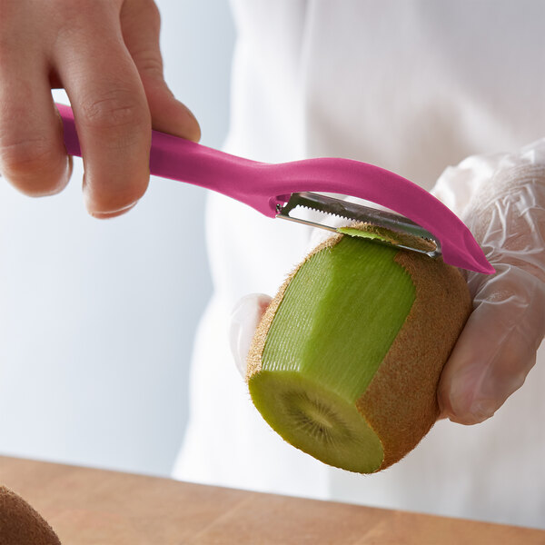 A person using a Victorinox pink straight vegetable peeler to peel a kiwi.