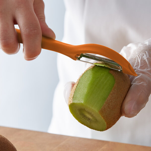 A person using a Victorinox orange vegetable peeler to peel a kiwi.