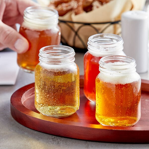 A group of Acopa Rustic Charm mini mason jars of beer on a tray.