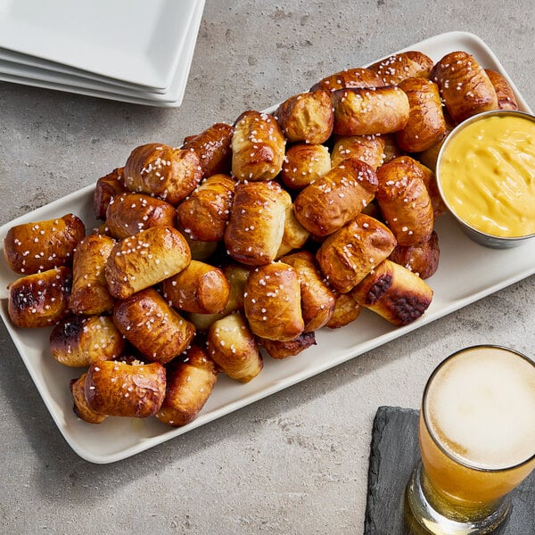 A plate of Dutch Country Foods soft pretzel nuggets with a glass of beer.