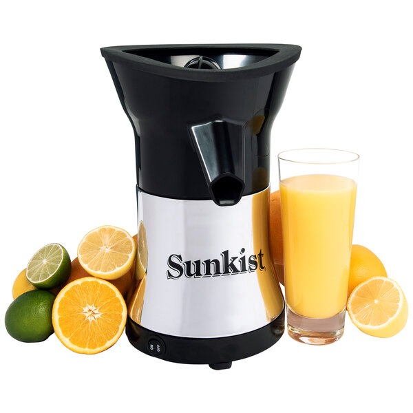 A Sunkist Pro Series citrus juicer with a glass of orange juice and limes and oranges nearby.