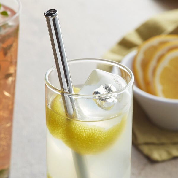 A glass with a Barfly stainless steel straw in it with a lemon slice.