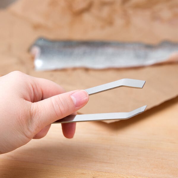 A person's hand using Thunder Group stainless steel culinary tweezers to pick up fish.
