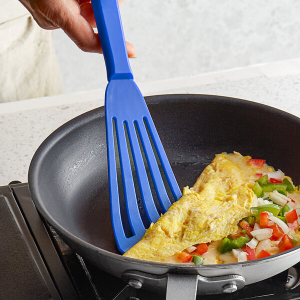A person using a Dexter-Russell blue slotted spatula to stir food in a pan.