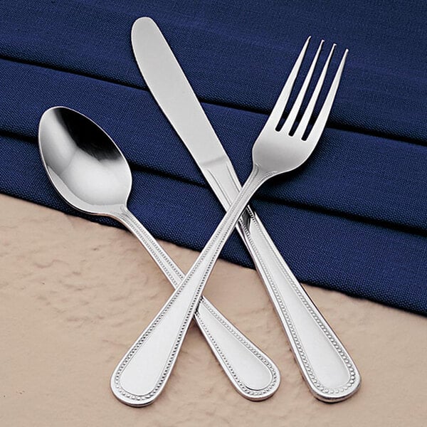 A Libbey stainless steel dinner fork and spoon on a blue napkin.