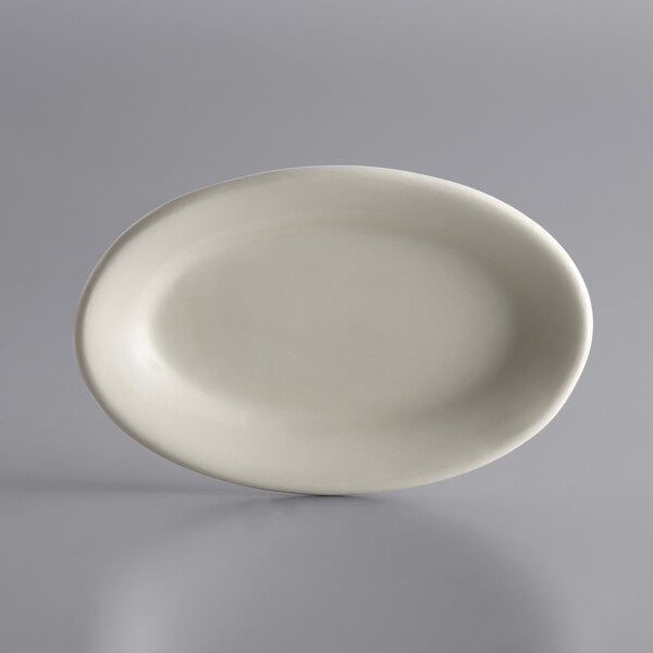 A Libbey Ultima Cream White oval stoneware platter on a gray surface.