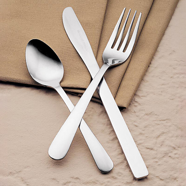 A Libbey stainless steel teaspoon and a fork on a napkin.