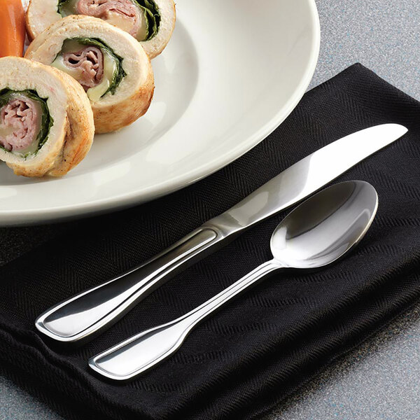 A plate of food with a Libbey Wellington stainless steel teaspoon and knife.