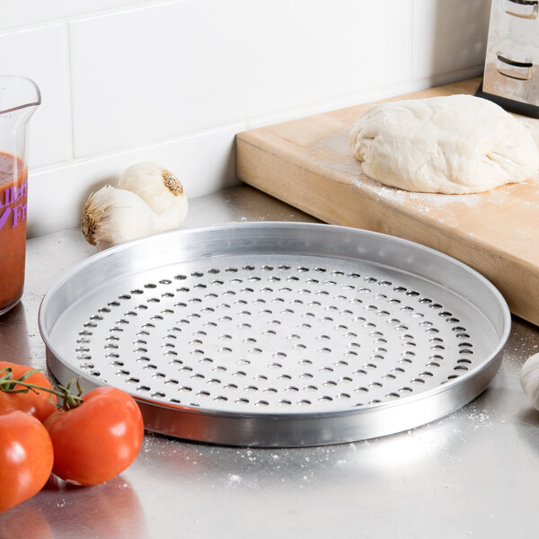 An American Metalcraft Super Perforated Pizza Pan with tomatoes on it.
