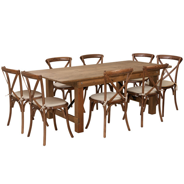 A Flash Furniture wooden folding farm table with chairs and white cushions around it.