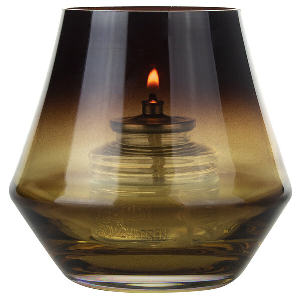 A Sterno amber glass votive candle holder with a lit candle inside.