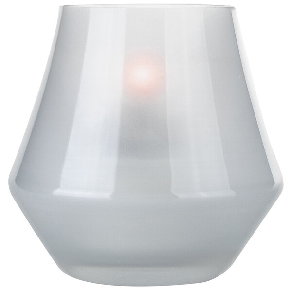 A white Sterno Cymbal glass votive candle holder with a light inside.