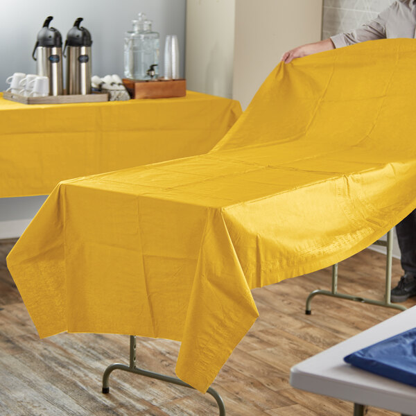 A person using a Hoffmaster Sun Yellow Cellutex table cover on a table.