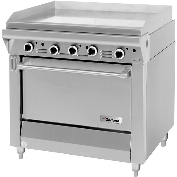 A stainless steel Garland gas range with a griddle top over a standard oven.